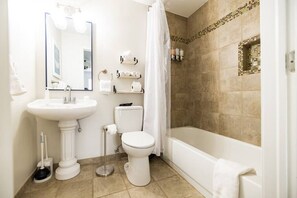 Une salle de bain avec un lavabo sur colonne, des toilettes et une baignoire.
