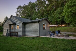 Une maison à deux étages dotée d’un patio aménagé avec des meubles d’extérieur et un foyer.