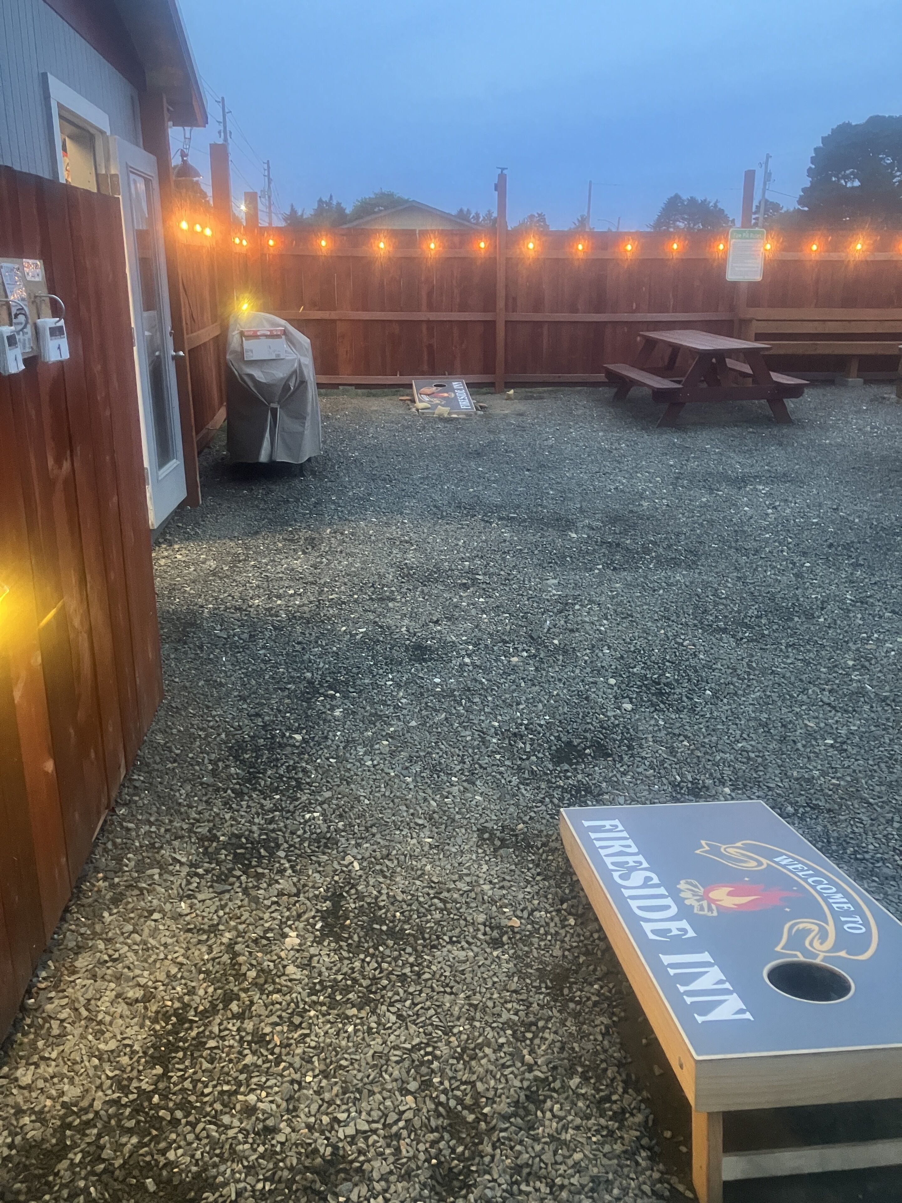 A backyard with a covered grill, a picnic table, and a sign for 'KIRK'S INN'.