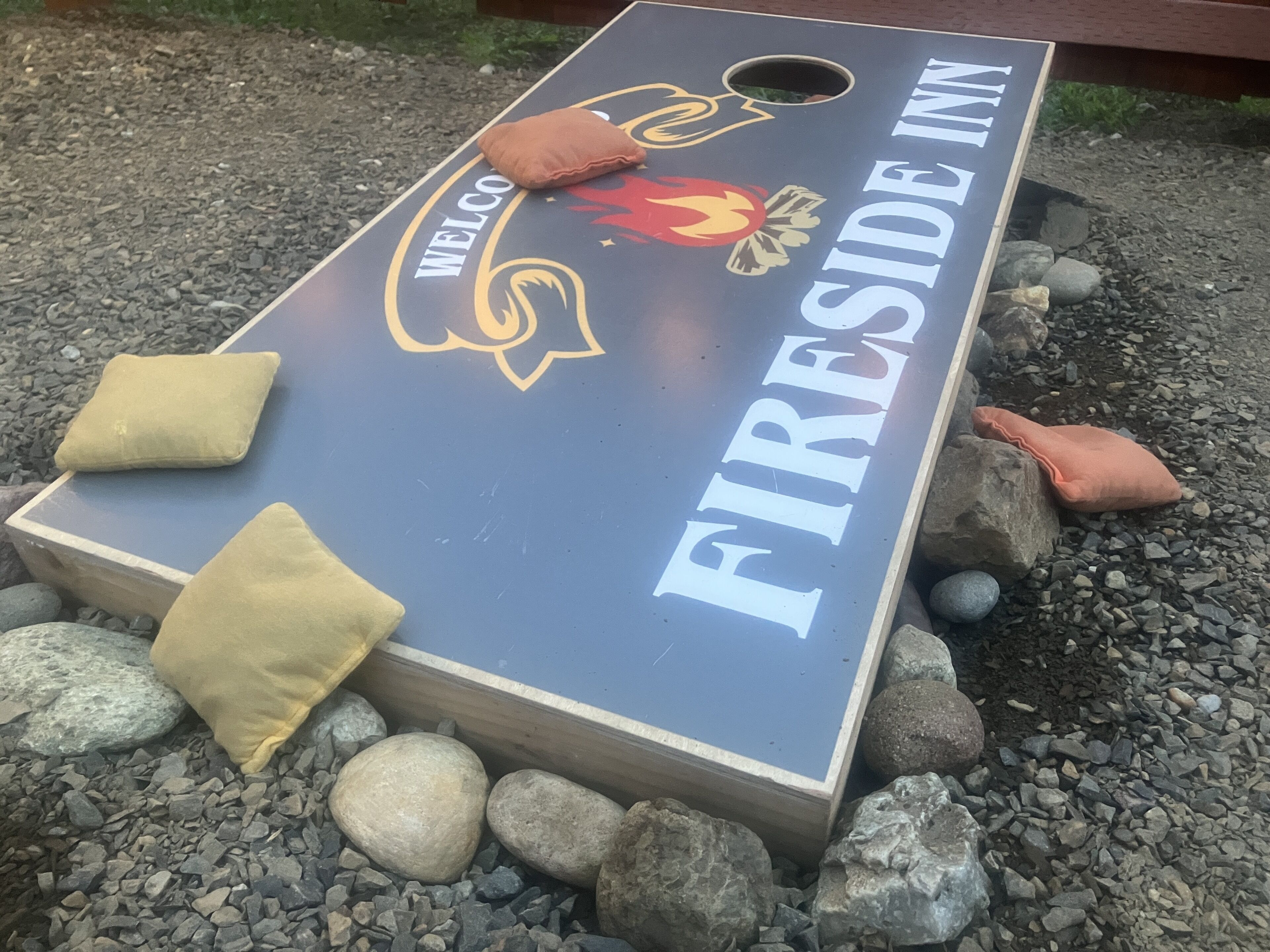 Un cartello di benvenuto per Fireside Inn, con il logo di una fiamma e un'accogliente area salotto con cuscini.