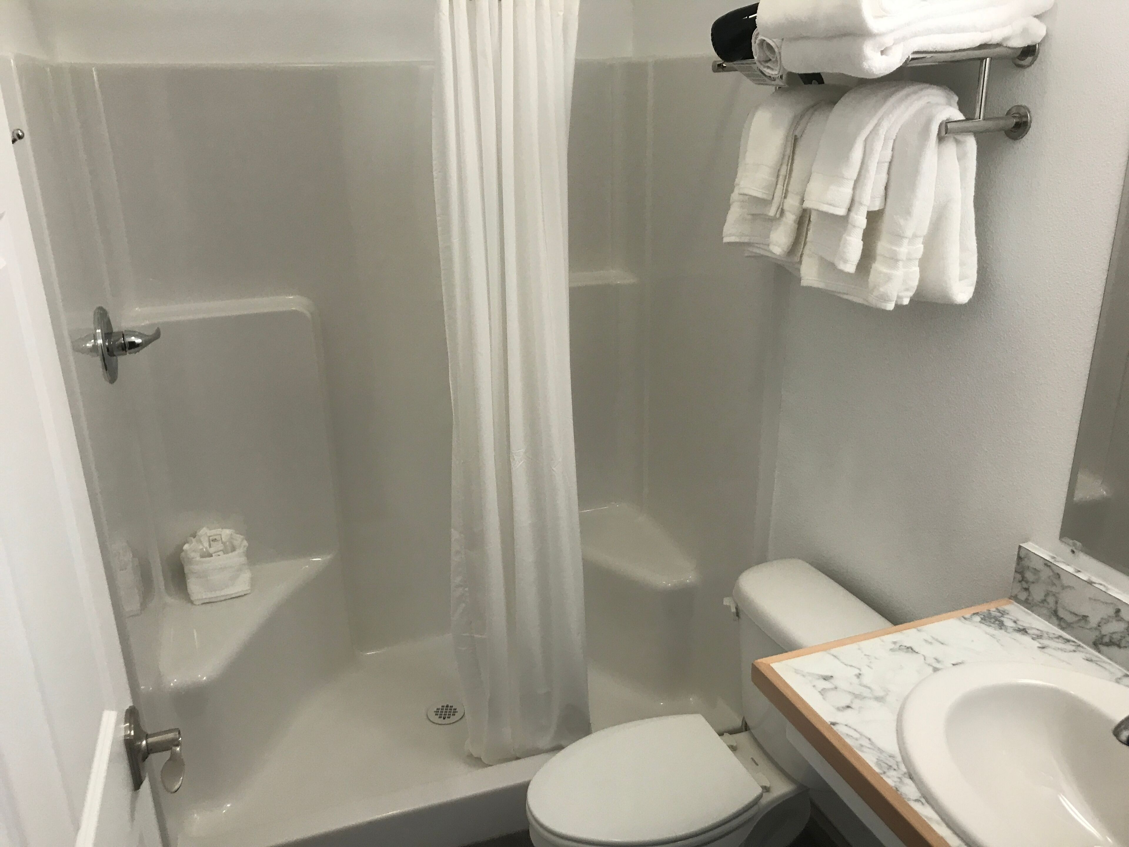 Un baño con cabina de ducha de vidrio, inodoro y lavamanos con encimera de mármol.