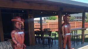 Two wooden statues of men under a covered patio area with tables and chairs. - The Fireside Inn (Long Beach)