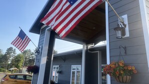 A house with two American flags on the porch, a car parked in front, and a hanging flower basket. - The Fireside Inn (Long Beach)