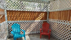 A covered patio area with two Adirondack chairs, a wooden fence, and a lattice overhead. - A newly remodeled 1BD&1BR private whole Guest-home to yourself! (Lancaster)