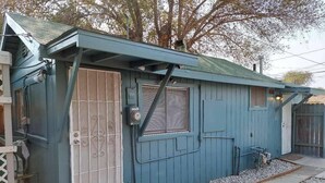A small, single-story building with a blue exterior, a metal gate, and a window with blinds. - A newly remodeled 1BD&1BR private whole Guest-home to yourself! (Lancaster)
