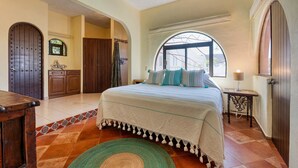 Een slaapkamer met een bed, een raam, een deur en een klein tafeltje.