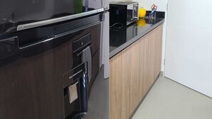 Une cuisine moderne avec des meubles en bois, un plan de travail noir et un four encastré.
