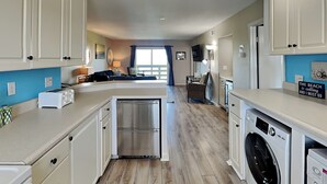 Una cocina moderna con armarios blancos, un refrigerador de acero inoxidable, horno empotrado y lavadora.