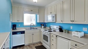 Una cocina con armarios blancos, estufa, lavamanos y ventana.