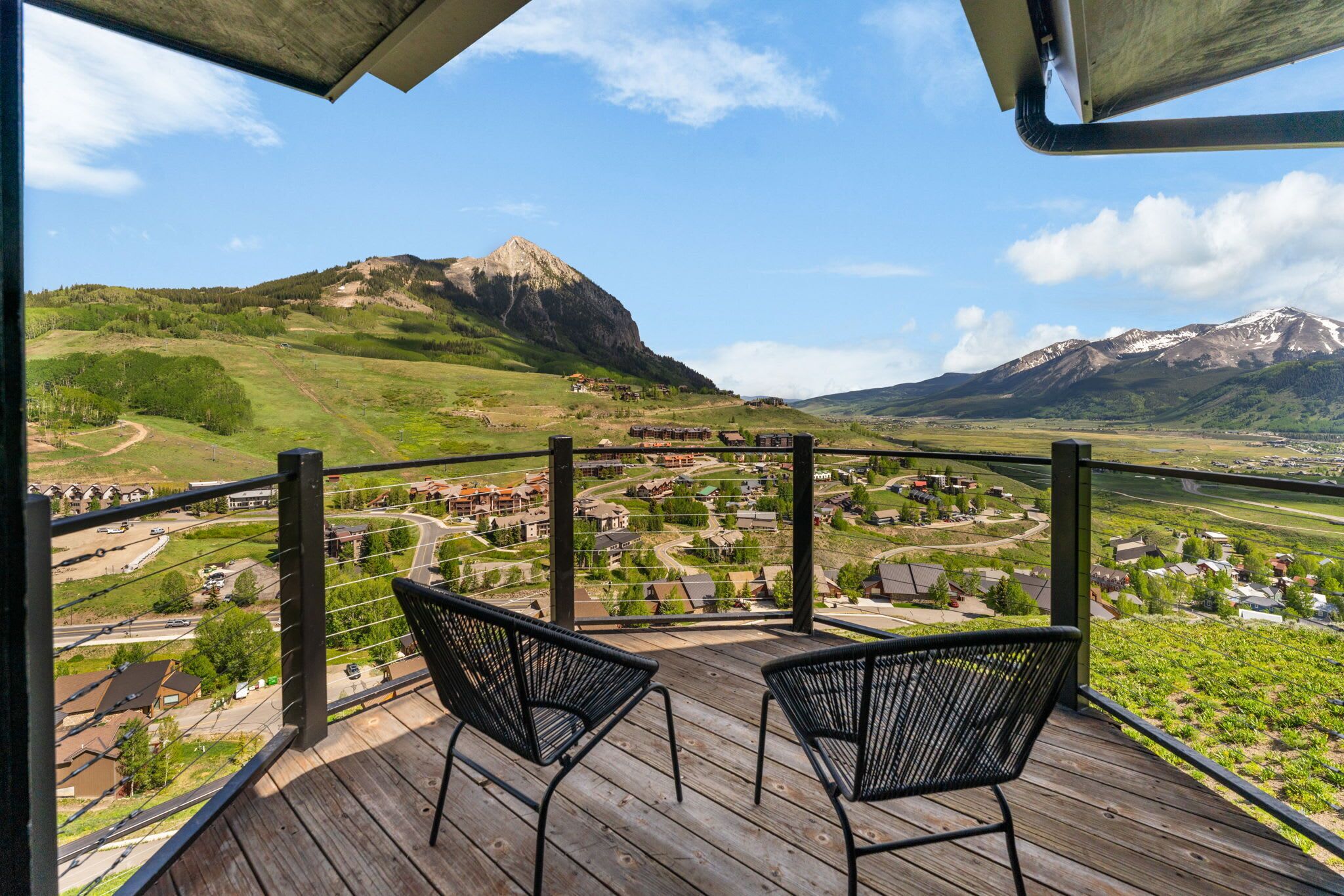 Un balcone con due sedie affacciato su un paesaggio montuoso con un villaggio sottostante.