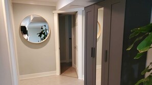 Un couloir avec un miroir, une armoire et une plante.