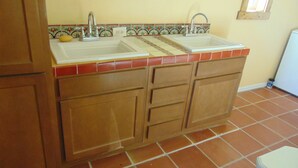 Una cocina con dos fregaderos, armarios de madera y un salpicadero de azulejos.