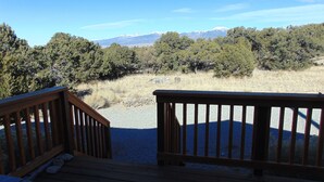 Una terraza de madera con vistas a un paisaje montañoso y un bosque denso.