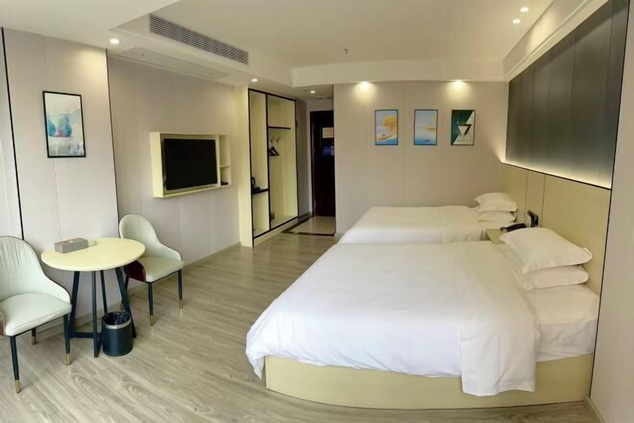 A hotel room with a bed, a TV, a desk, and chairs.