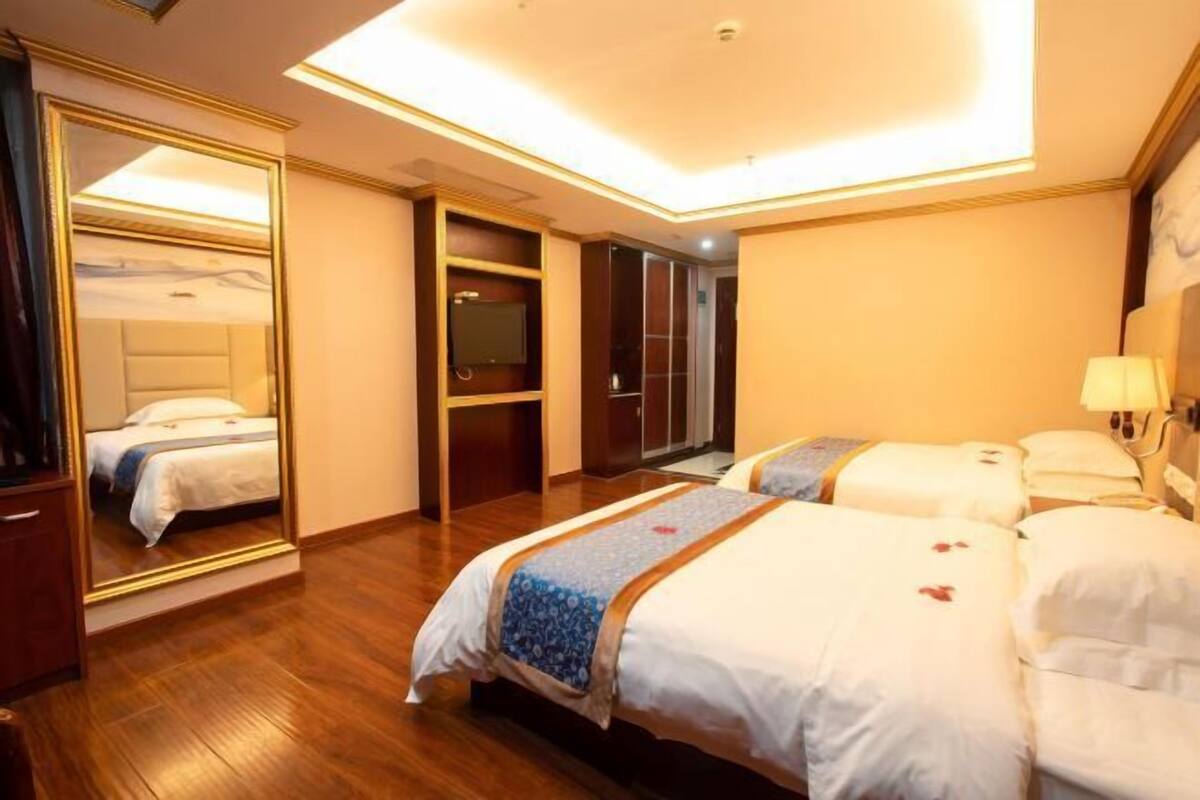 Ein Hotelzimmer mit einem großen Bett, einem Spiegel, einem Kleiderschrank und einem Nachttisch.