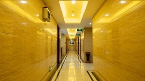 A long, well-lit hallway with marble walls and a reflective floor, leading to a door at the end. - Xiangju Business Hotel (Qingyuan Gulongxia Meilin Plaza) (Qingyuan)