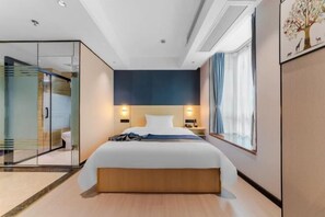 Ein modernes Hotelzimmer mit einem großen Bett, Nachttischlampen, einer Glastrennwand und Blick ins Freie.
