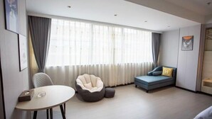 A modern room with a round table, a bean bag chair, a sofa, and a large window with curtains. - Xiangju Business Hotel (Qingyuan Gulongxia Meilin Plaza) (Qingyuan)