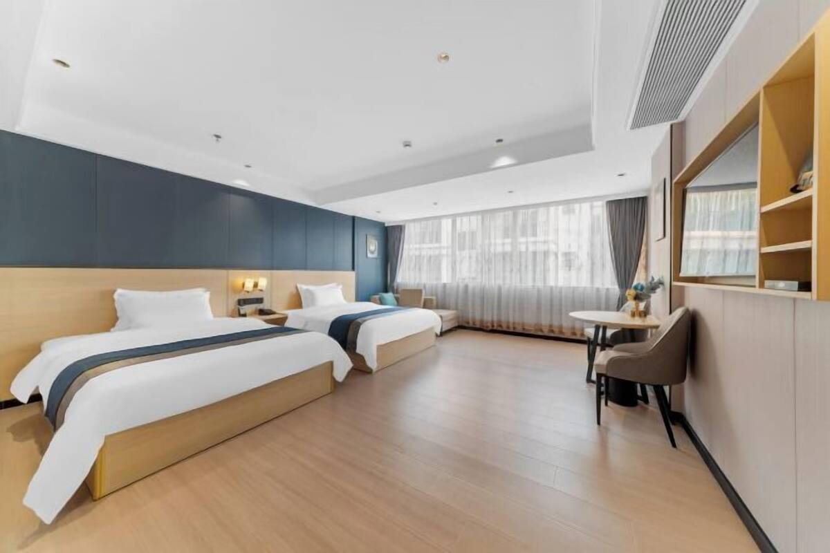 Ein Hotelzimmer mit zwei Betten, einem Esstisch und einem Stuhl.