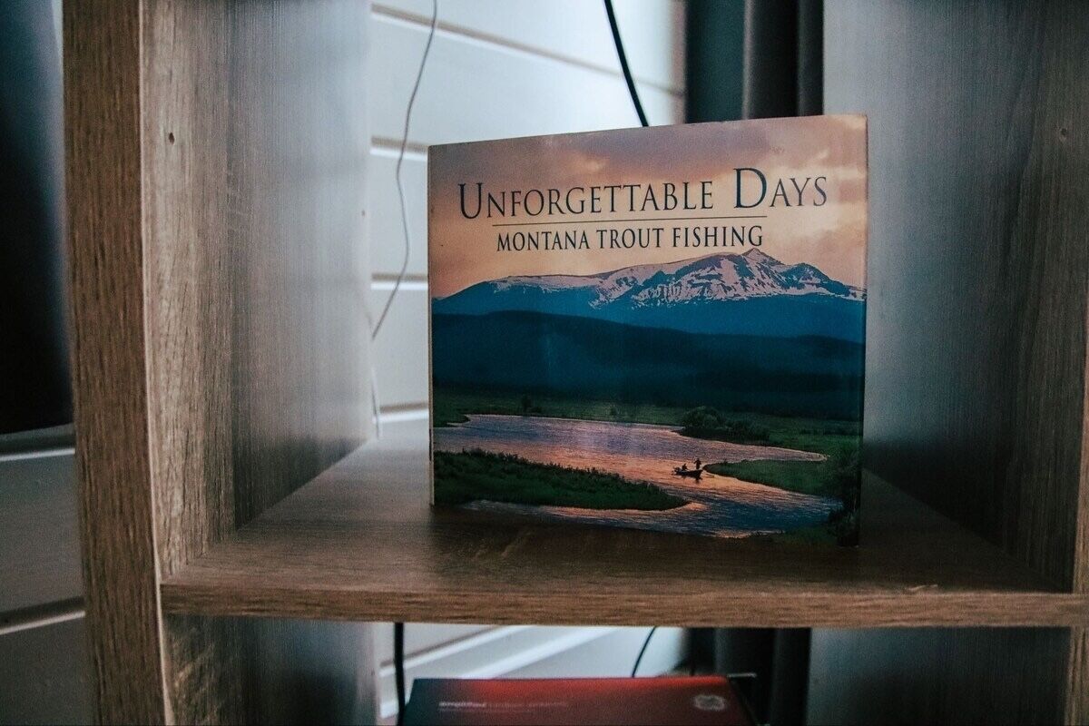 Un libro titulado 'Unforgettable Days Montana Trout Fishing' sobre una estantería de madera.