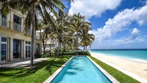 A poolside view of a beachfront hotel with a clear blue pool, palm trees, and a sandy beach. - Paradise Beach Villa, OCEANFRONT~Paradise Island~ (Paradise Island)