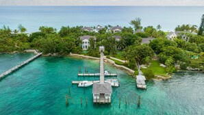 An aerial view of a coastal property with a dock leading to a house surrounded by lush greenery and palm trees. - Paradise Beach Villa, OCEANFRONT~Paradise Island~ (Paradise Island)