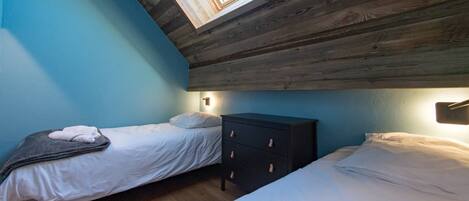 A bedroom with two beds, a wooden ceiling, and a skylight.