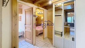 A wooden interior with a bed, a chandelier, and a sliding door leading to another room.