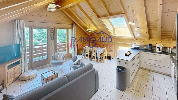 A spacious wooden cabin with a dining area, sofa, and kitchen.