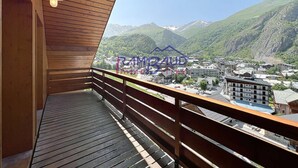 A wooden balcony with a view of a town and mountains.