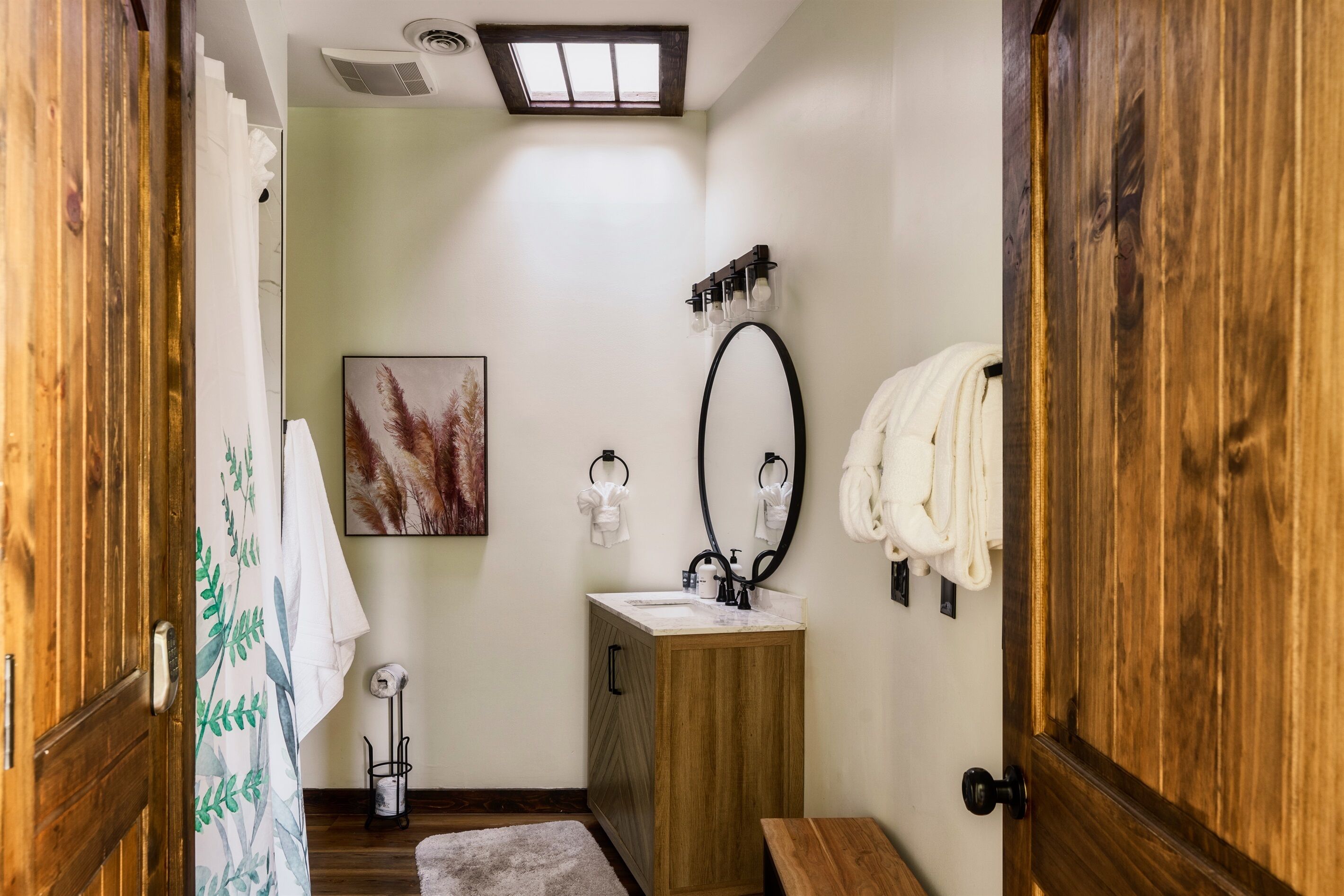 Baño con tocador de madera, espejo y cortina de ducha.