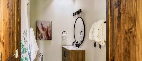 Baño con tocador de madera, espejo y cortina de ducha.