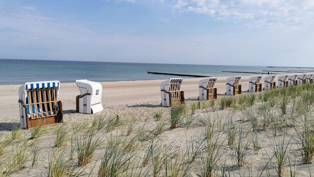Una playa con sillas de playa y una caravana blanca.