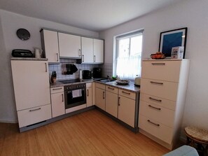 A compact kitchen with white cabinets, a built-in oven, and a window providing natural light.