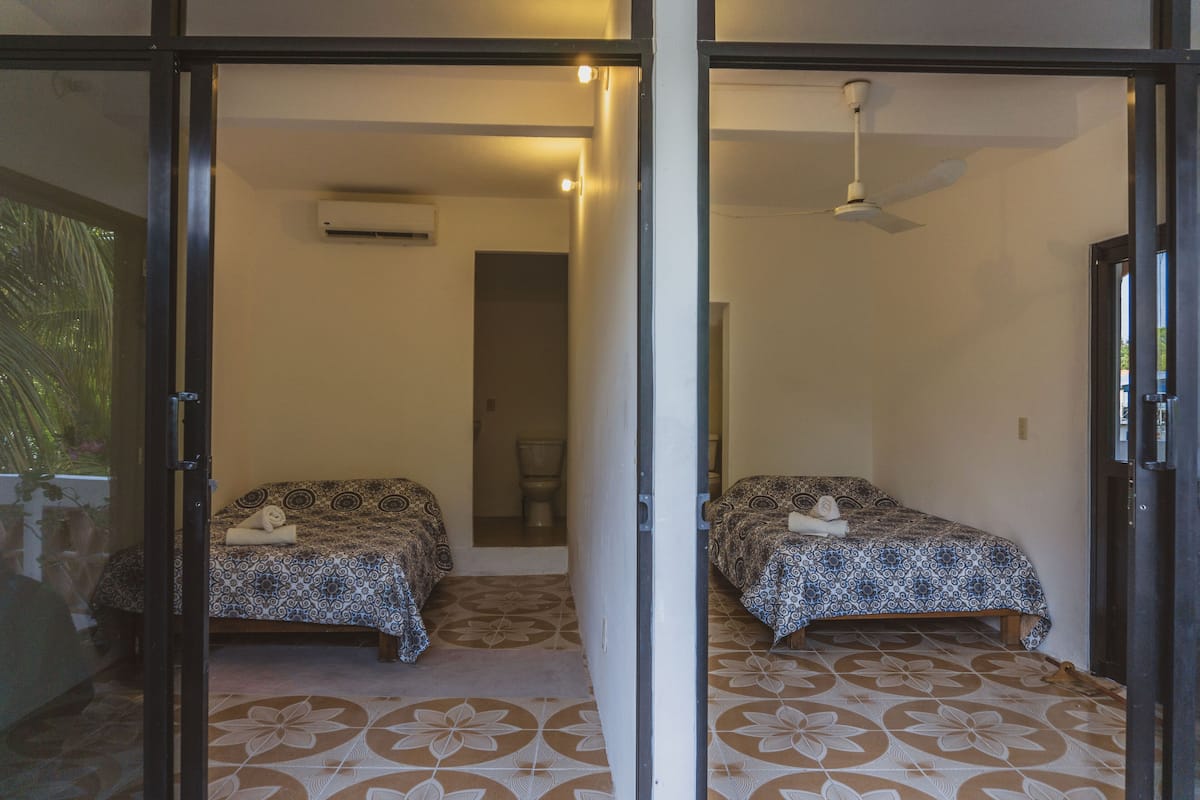 Une chambre avec deux lits, un climatiseur et un ventilateur de plafond.