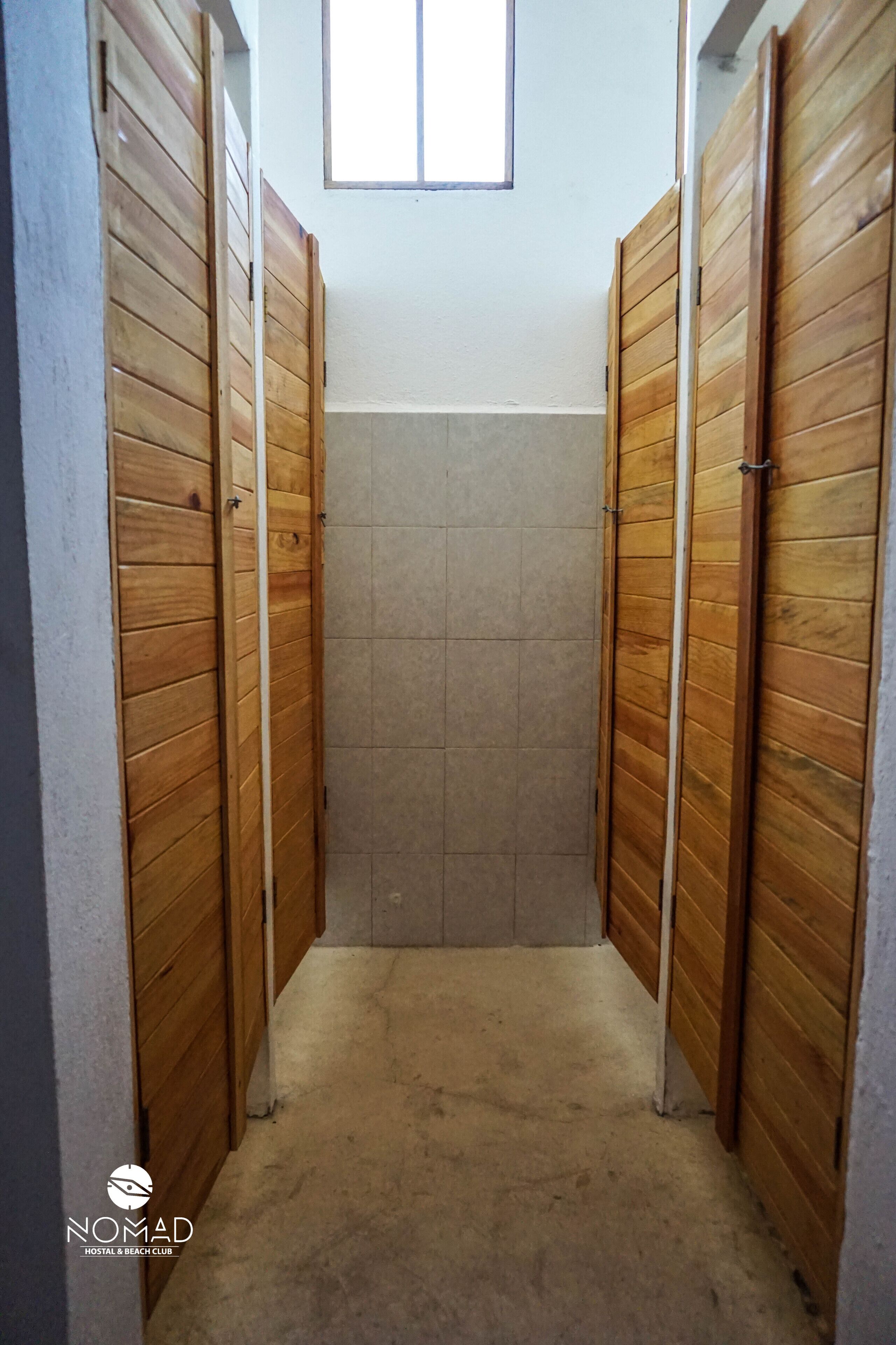 A narrow hallway with wooden doors and a tiled wall.