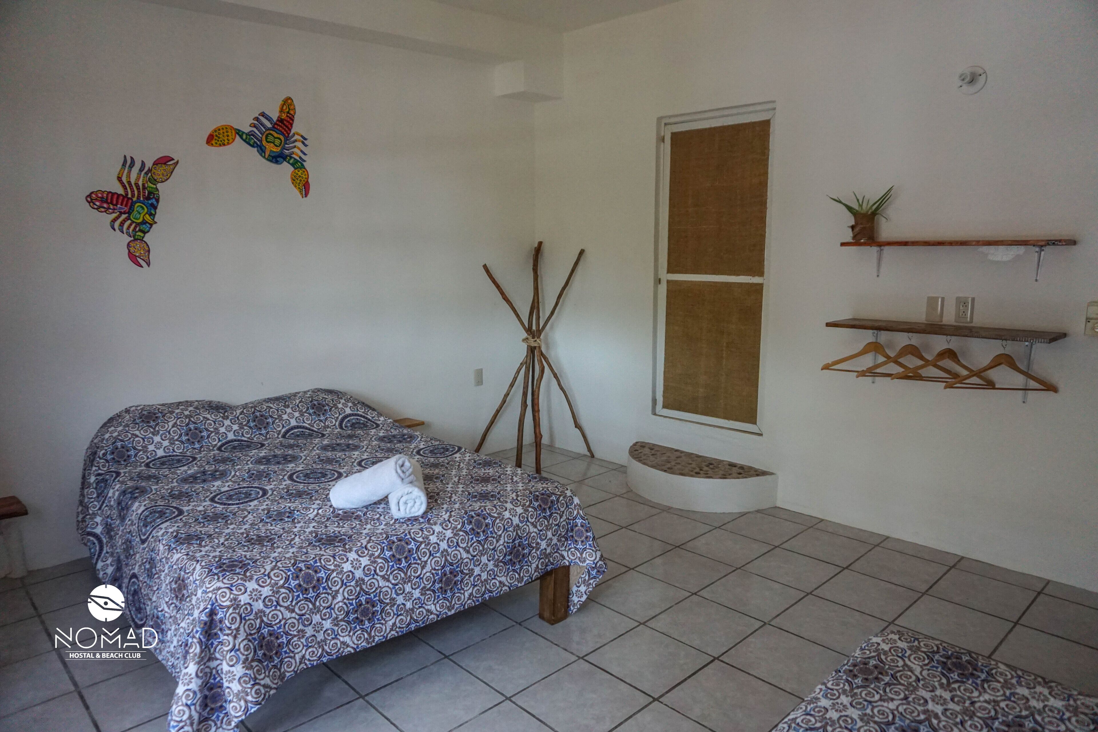A room with a bed, a wall-mounted shelf with a plant, and a wall decoration.