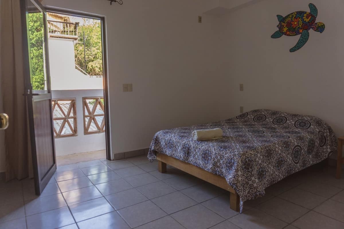 Une chambre à coucher comprenant un lit, une porte donnant sur un espace extérieur et un élément décoratif mural.
