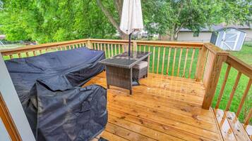 A wooden deck with a covered seating area and a table, surrounded by a wooden railing.