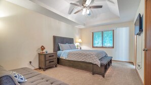 Un dormitorio con cama, mesita de noche, lámpara y ventilador de techo.