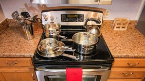 Una cocina con estufa, horno y ollas.