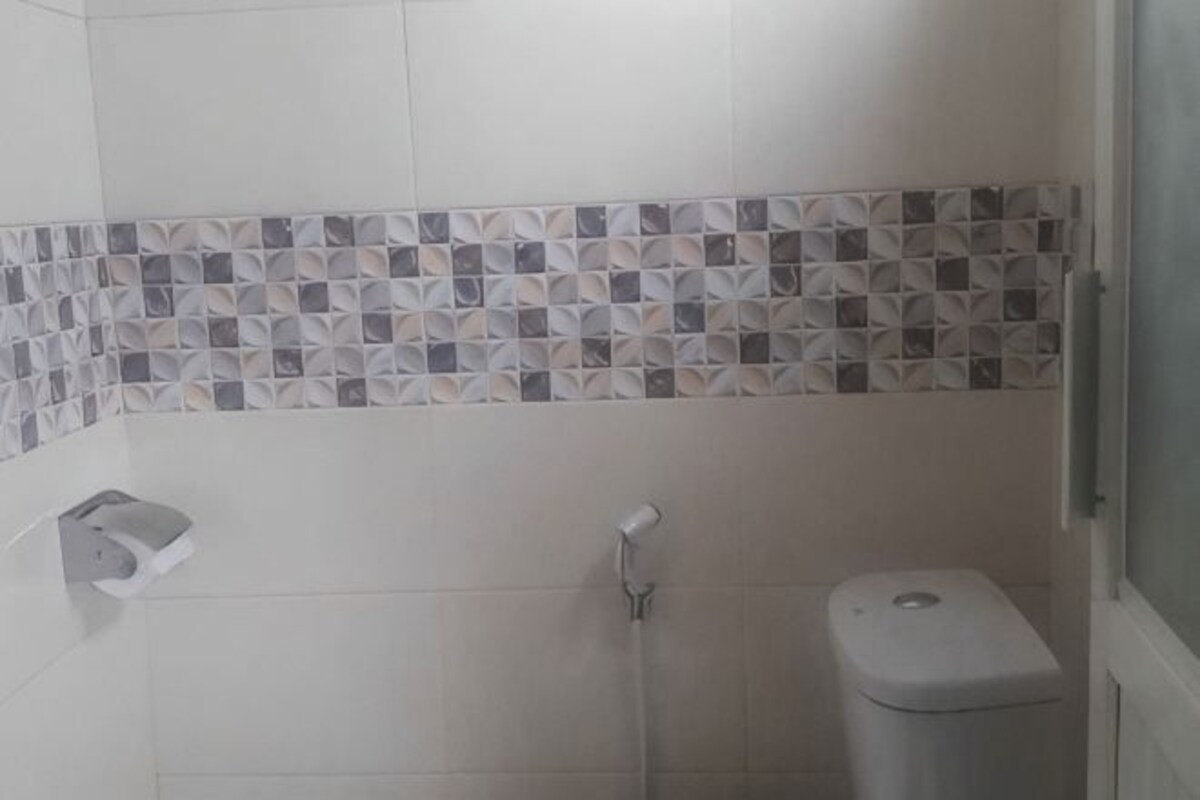 A bathroom with a tiled shower area, a toilet, and a paper towel dispenser.