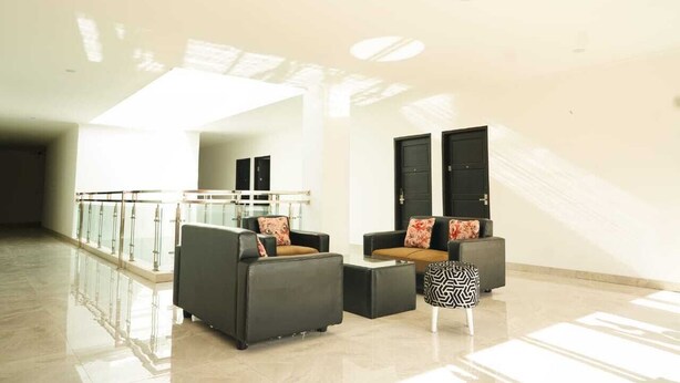 A spacious lobby with a high ceiling, a glass railing, and a seating area with sofas and a coffee table. - Mel's Inn Manado (Manado)