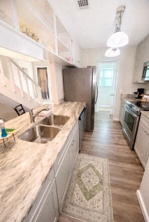 A modern kitchen with granite countertops, stainless steel appliances, and a walk-in pantry.