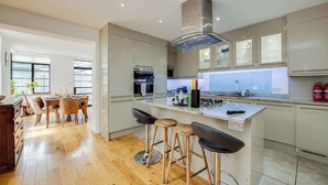 A modern kitchen with a central island, bar stools, and a dining area with a wooden table and chairs.
