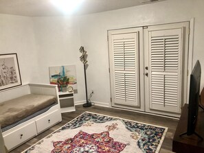 A living room with a sofa, a patterned rug, a painting, a clock, and a TV on a stand. - Mid-Century house in the Trees (Smyrna)