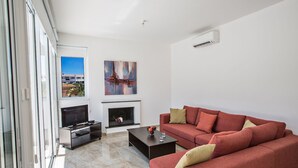 Una sala de estar moderna con un sofá rojo, un televisor de pantalla plana, chimenea y un ventanal con vistas al exterior.