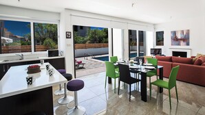 Una cocina moderna con comedor, piscina y sala de estar con sofá y sillones.