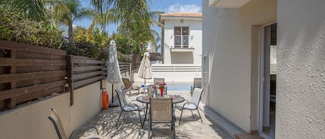 A patio with outdoor seating, a pool, and a view of a building with a tiled roof.