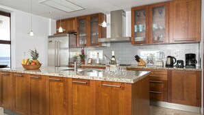 A modern kitchen with wooden cabinets, stainless steel appliances, and a granite countertop. - Blue Dove | Beach Front - Located in  Beautiful Cupecoy with Private Pool (Cupecoy)